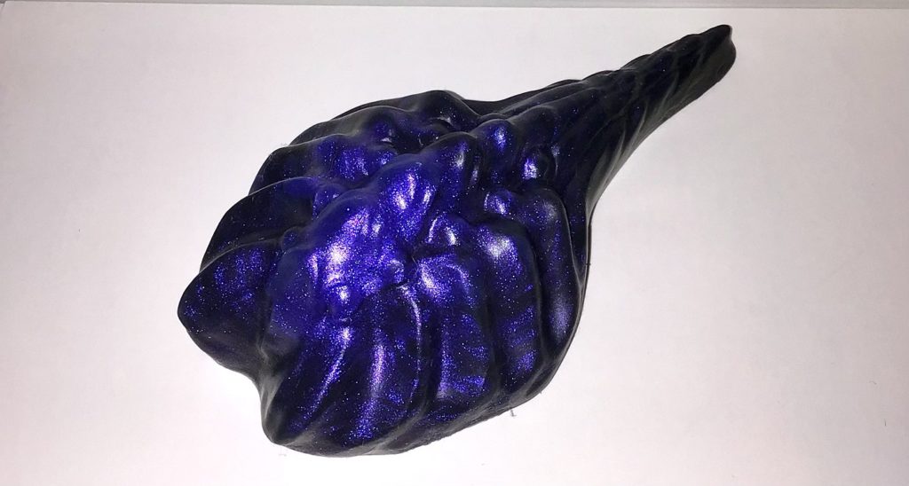 A small grinder with bumps forming a spine, ridges along the side, and a small tail. It's black and shimmery violet.