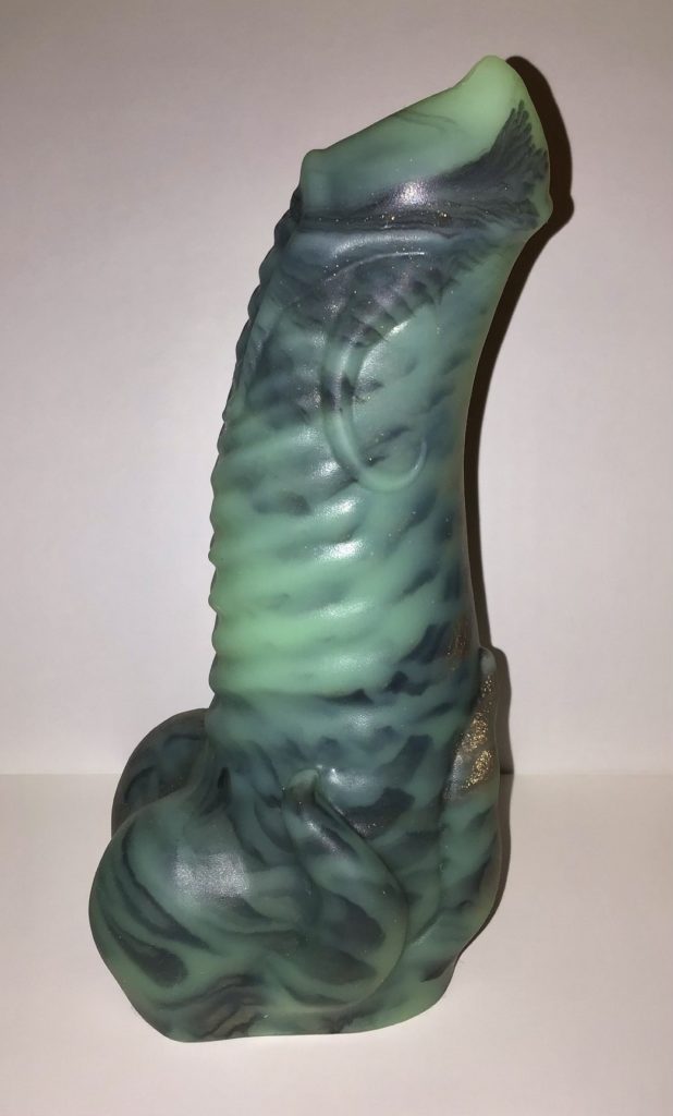A stout, ribbed shaft with a pointed tip, tight balls, and tentacles winding along the side and base. It's translucent green with black and copper marbled throughout.